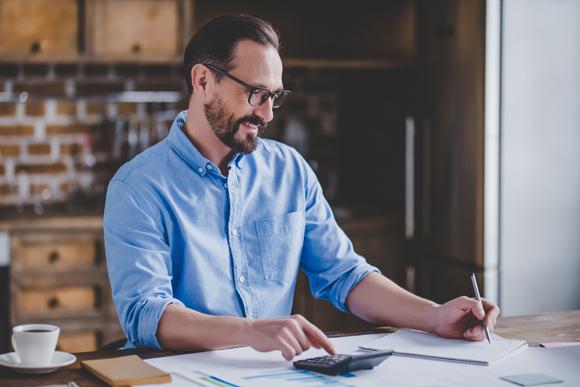 mężczyzna robiący obliczenia na kalkulatorze